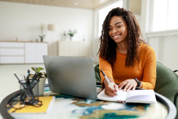 A young women sat at a table sing the laptop