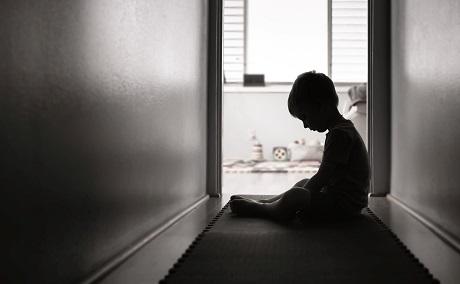 sad child sitting alone in a corridor.